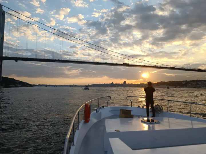 Gün batımında Boğaziçi Köprüsü altından geçen yatın pruvası
